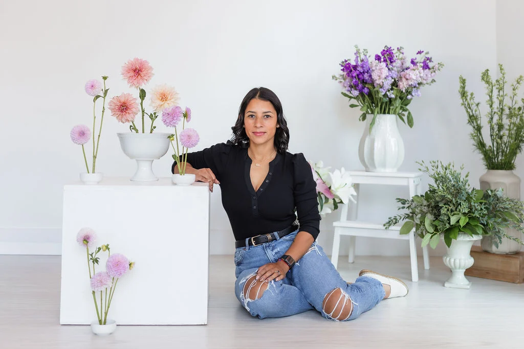 Celenia seated in the Lavender Lane Events studio surrounded by dahlias and arrangements