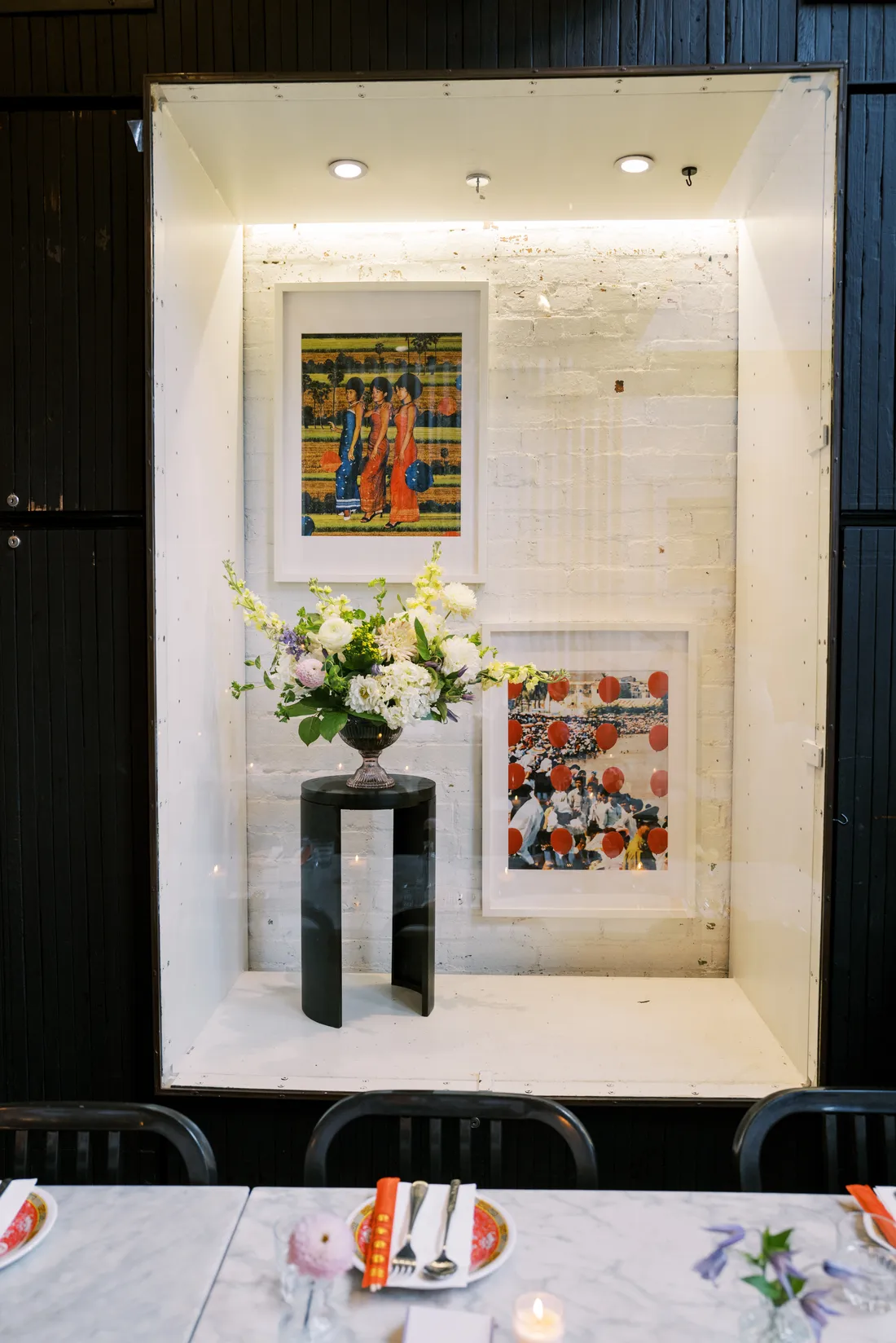 Compote wedding arrangement in a silver urn in a lit alcove above marble reception tables at Maketto