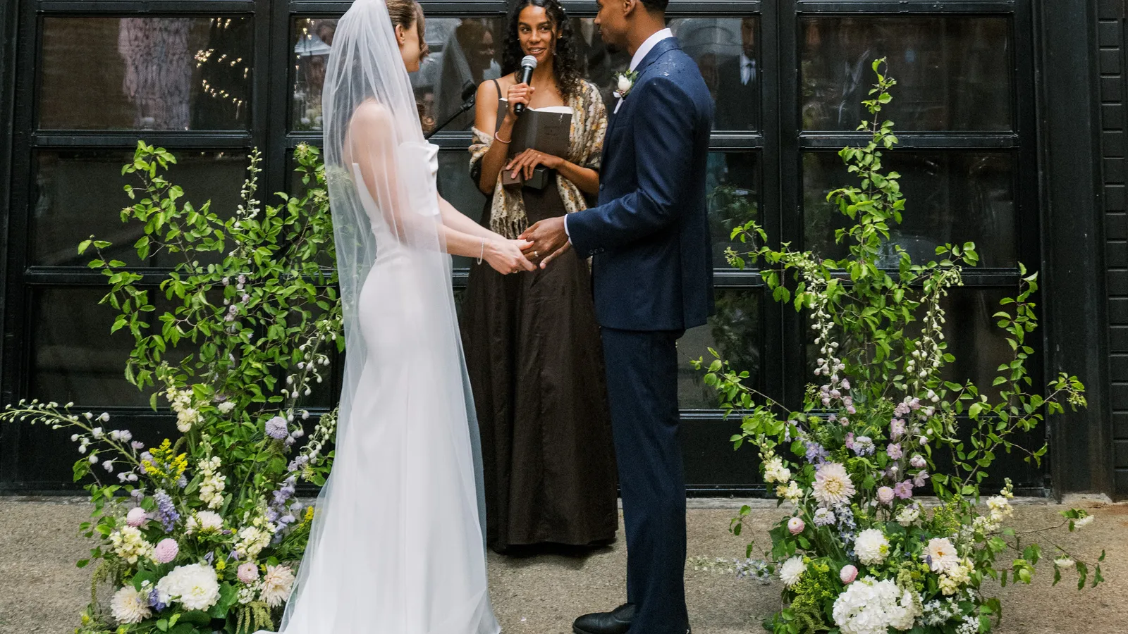 Courtyard wedding ceremony at Maketto, Washington DC, framed by two meadow floral installations against black garage doors