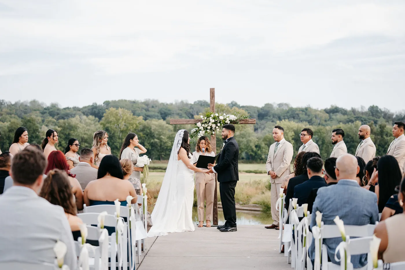 Outdoor wedding ceremony aisle with a floral-dressed wooden cross at Riverside on the Potomac in Leesburg, Virginia