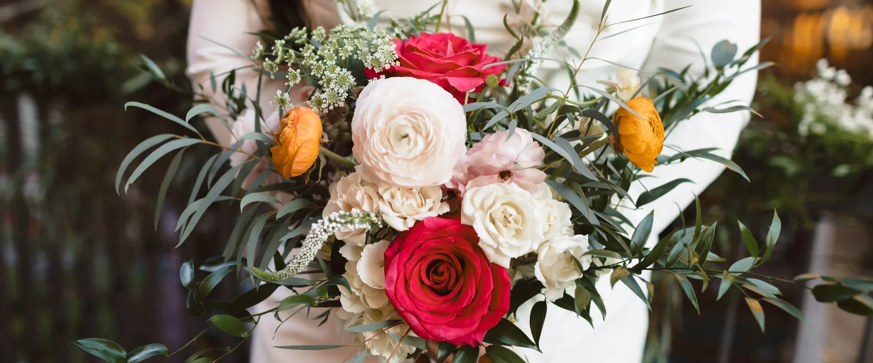 Bridal bouquet of crimson garden roses, marigold ranunculus and olive foliage at a Maketto wedding in Washington DC