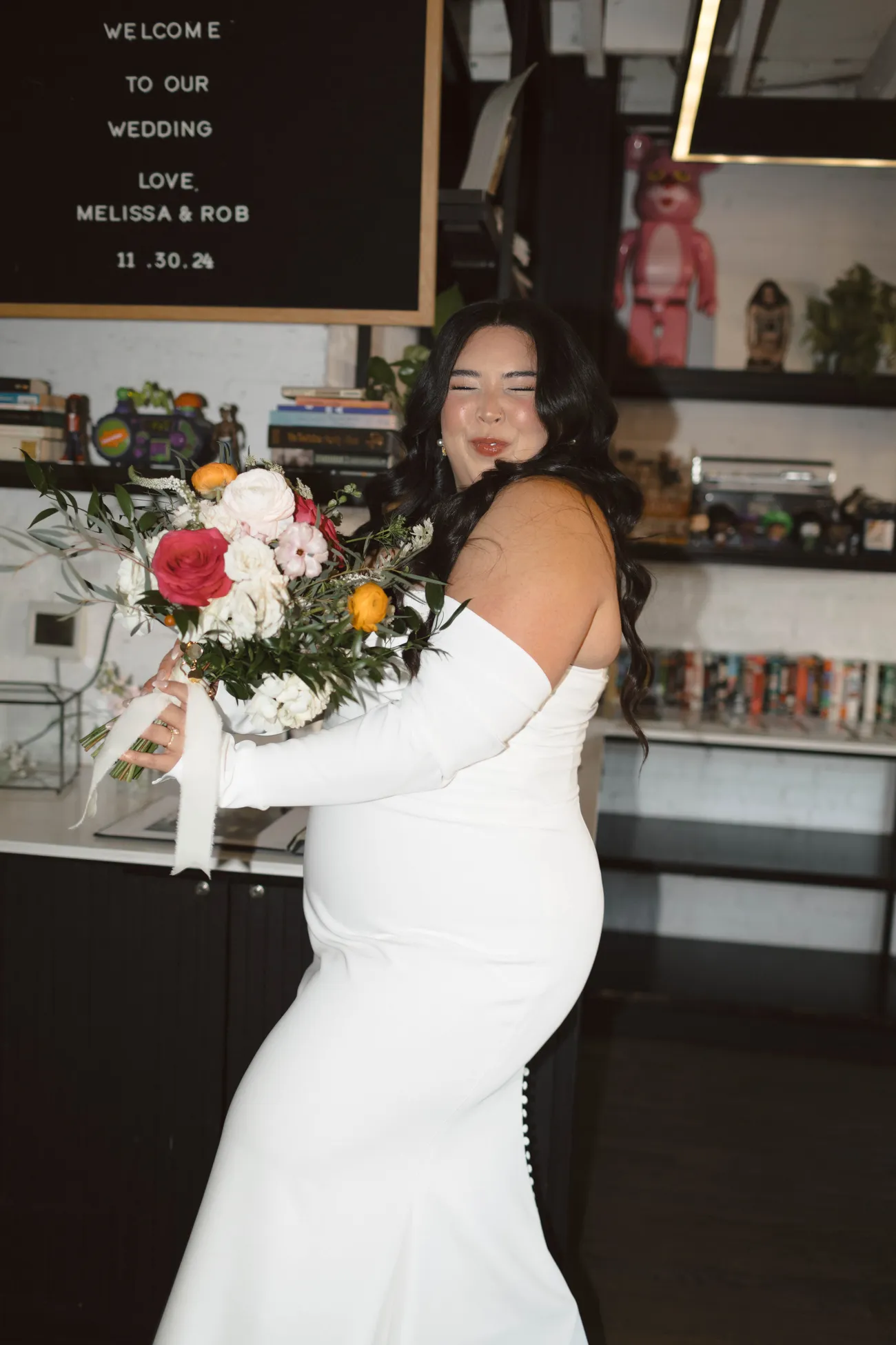 Bride laughing while holding a crimson and marigold bridal bouquet