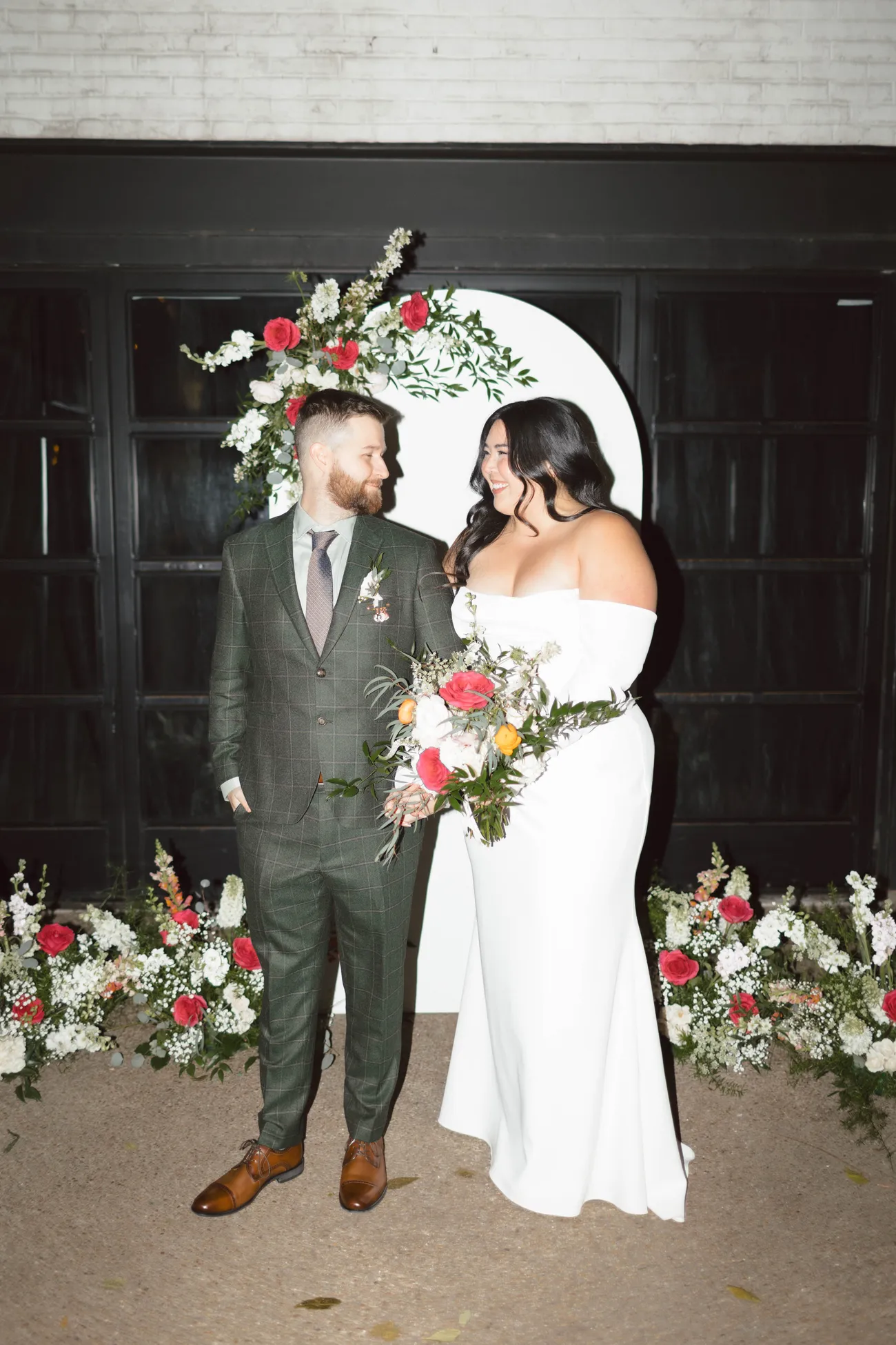 Bride and groom in front of a white floral arch at night at Maketto in Washington DC