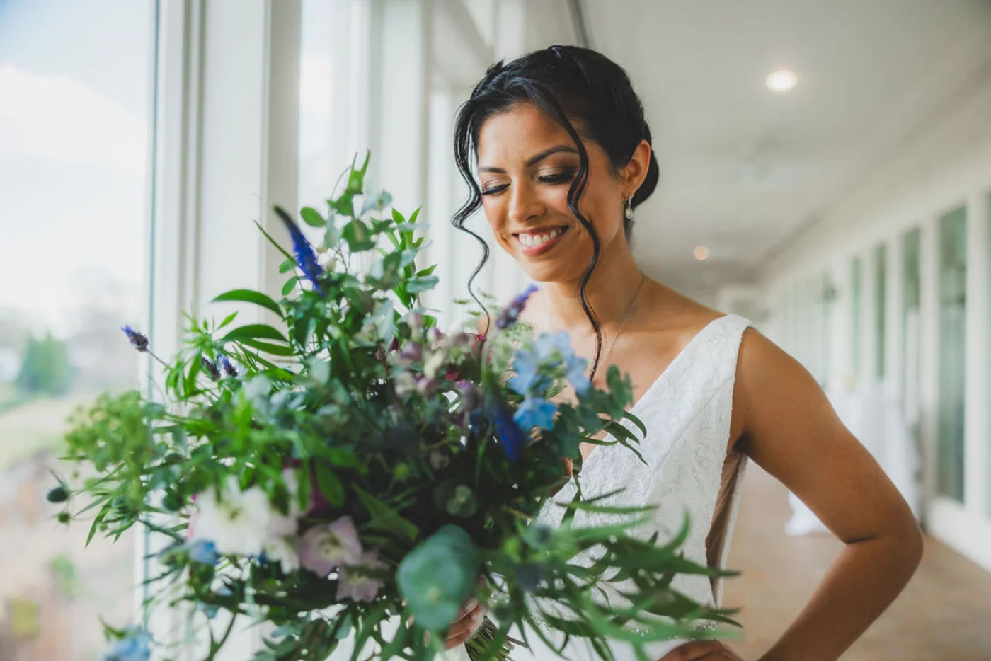 Bride holding a lush garden bouquet of delphinium, thistle and spring greenery at an Arlington, Virginia wedding