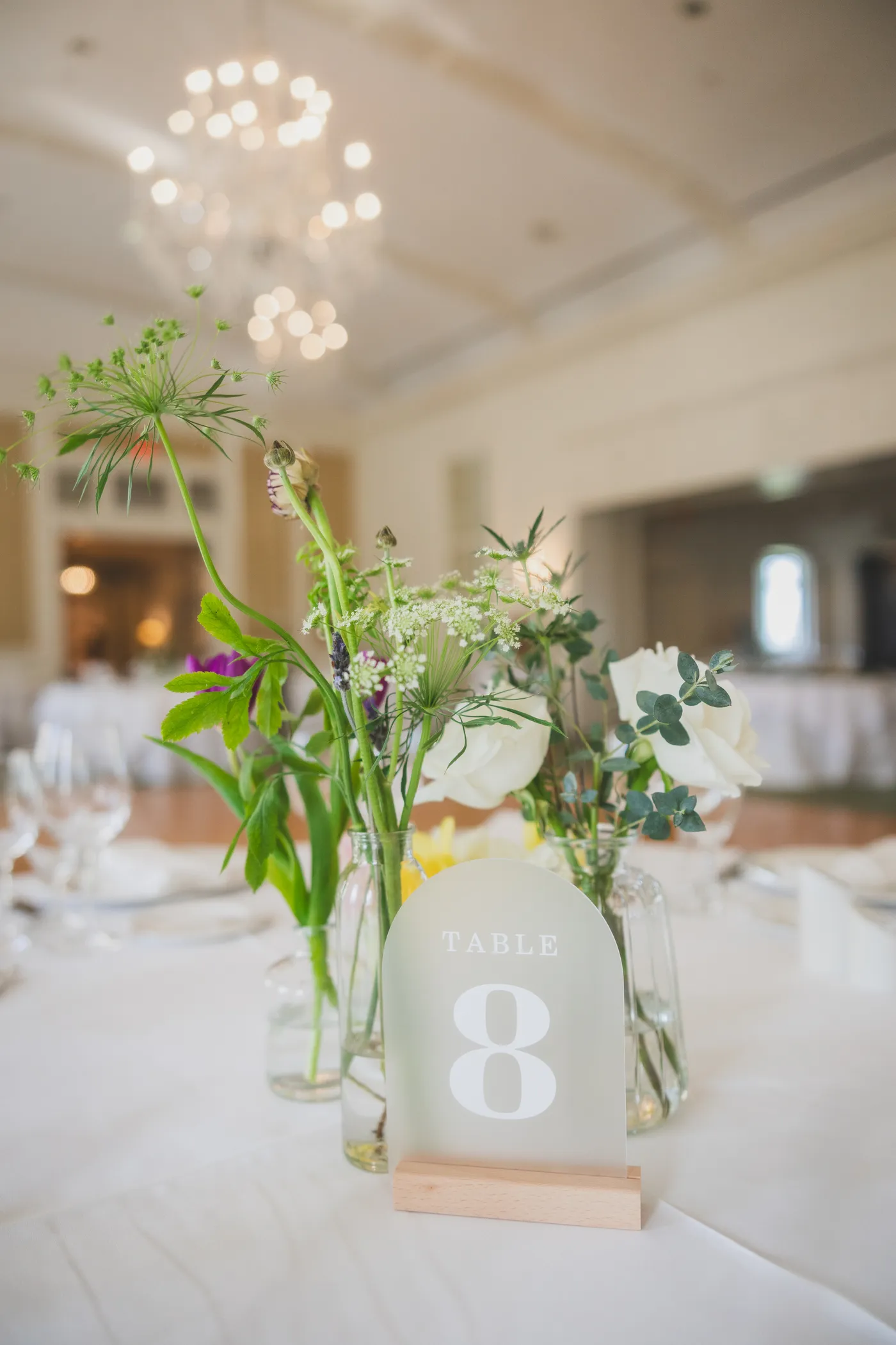 Collected bud vases with spring wildflowers on a wedding reception table
