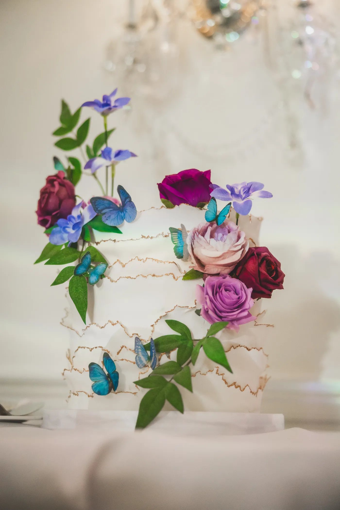 Wedding cake with jewel-toned sugar flowers and butterflies