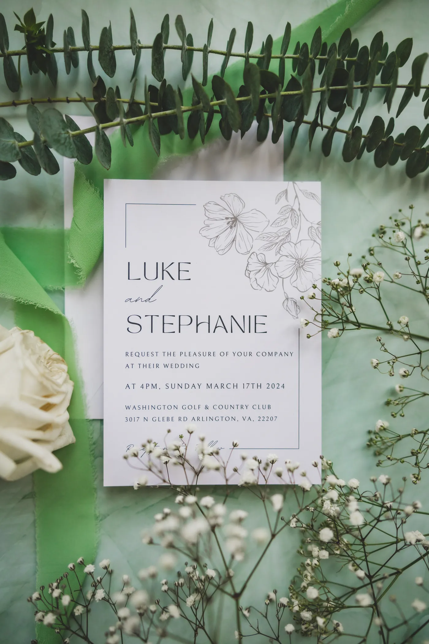 Spring wedding invitation flat lay with baby's breath and white roses